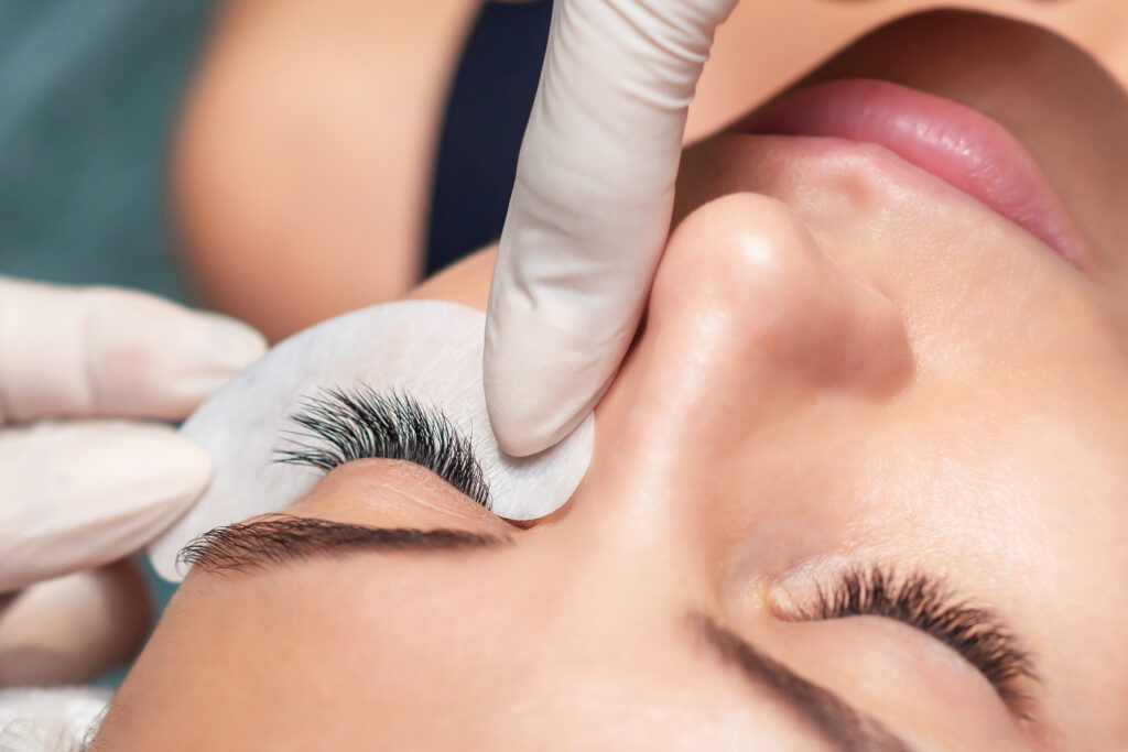 Young woman receiving extending the eyelashes in a beauty salon, close up, eyelash extension procedure